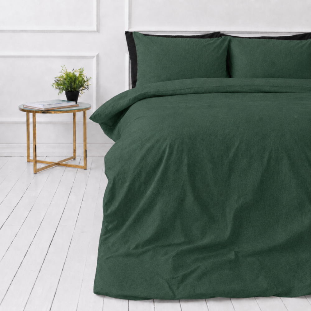 Linne sängkläder „Linen Dark Green“. Påslakanset 150x210, 140x200 cm, 150x200 cm, 160x200 cm, 180x200 cm, 200x200 cm, 200x220 cm, 240x220 cm. Mörkgrönt sängkläderset i linne på ett vitt golv med ett nattduksbord och en blomkruka.